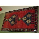 RED GROUND HAND KNOTTED WOOLLEN FLOOR RUG WITH SINGLE MARGIN AND TWO MEDALLIONS