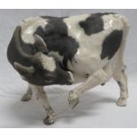 Raku pottery model of a standing cow with raised hind leg, height 24cm, length 30cm