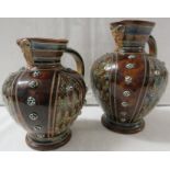 A pair of larger and smaller Doulton Lambeth 1876 satyr mask jugs, brown glaze with blue stripes,