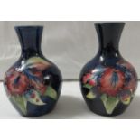 Pair of small Moorcroft pottery bottle vases, dark blue ground with tubelined decoration of