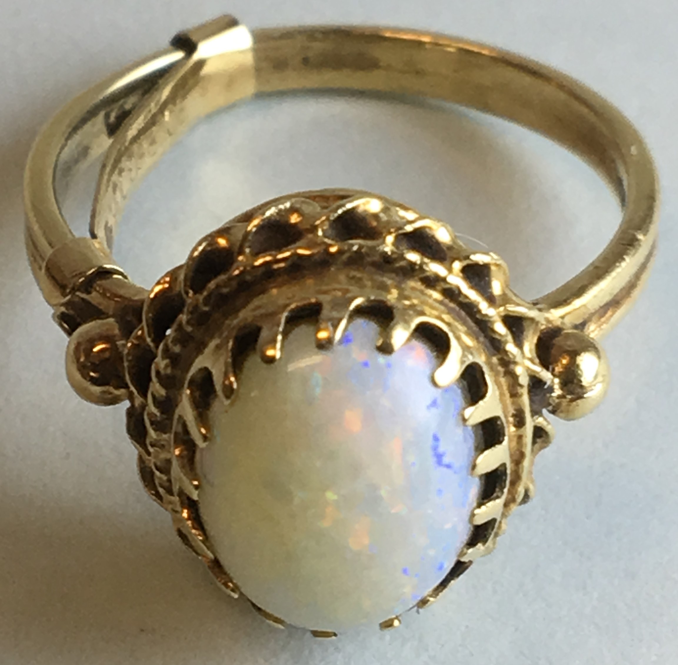 Yellow metal opal ring, the opal 10mm x 7mm in a claw setting, indistinct stamped mark to the