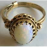 Yellow metal opal ring, the opal 10mm x 7mm in a claw setting, indistinct stamped mark to the