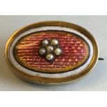 A small oval memorial brooch with rose engine turned enamel with a foliate setting of six seed