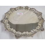 Silver circular tray with a scroll and scallop border, raised on three feet, marks for Sheffield,