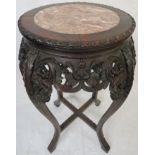 Far Eastern hardwood plant stand with foliate carving and a circular inlaid red marble top, on