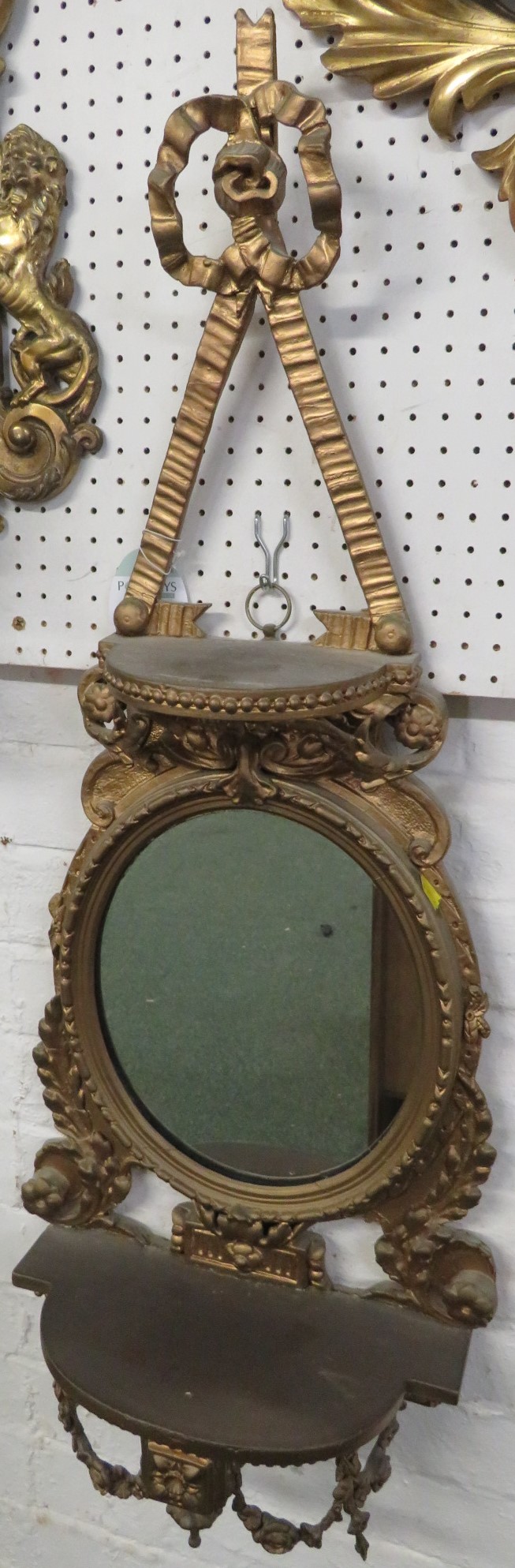 Gilt wood wall bracket with oval mirror and a shelf above and below, carved acanthus and swags and a