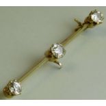 Yellow metal three-stone diamond bar brooch, the central cushion cut stone estimated at 0.6 ct,