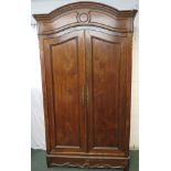 An early 19th century tall French oak armoire, two arch topped doors with long tooled brass