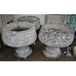 THREE COMPOSITE STONE GARDEN URNS ON PLINTHS WITH FLEUR DE LIS DESIGN