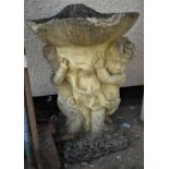 LARGE COMPOSITE STONE BIRDBATH IN FORM OF CLAMSHELL SUPPORTED BY TWO PUTTI (A/F)