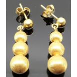 Pair of yellow metal triple-ball pendant earrings, the retainer of one earring is stamped 8K