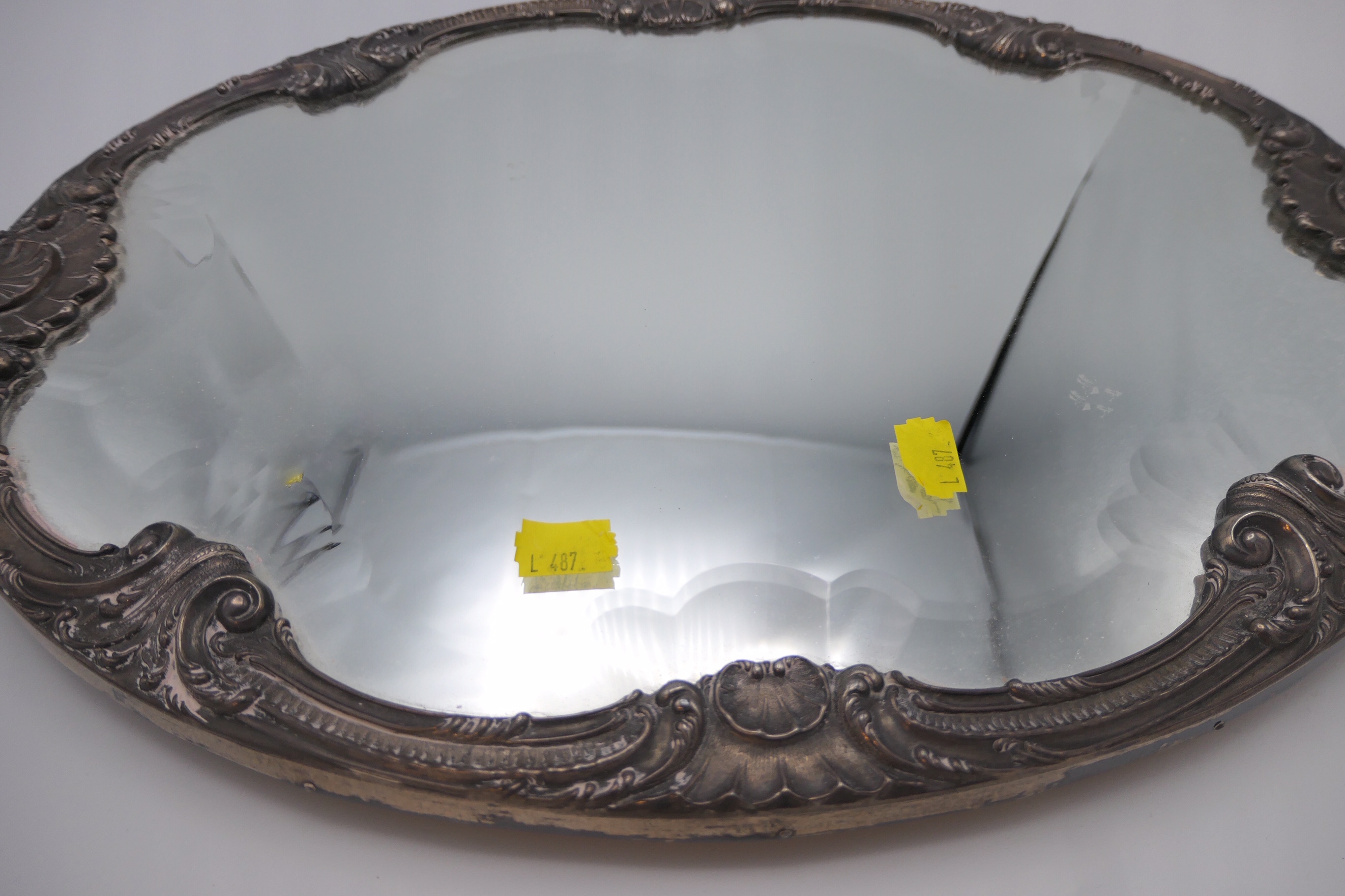 A shaped oval mirror tray with bevelled glass and mounted with a white metal frame decorated with - Image 2 of 2