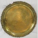 Large circular brass tray standing on four feet, the edge moulded with leaves and flowers, the