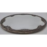 A shaped oval mirror tray with bevelled glass and mounted with a white metal frame decorated with