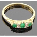 18 carat gold ring set with three emeralds separated by two pairs of very small diamonds, the