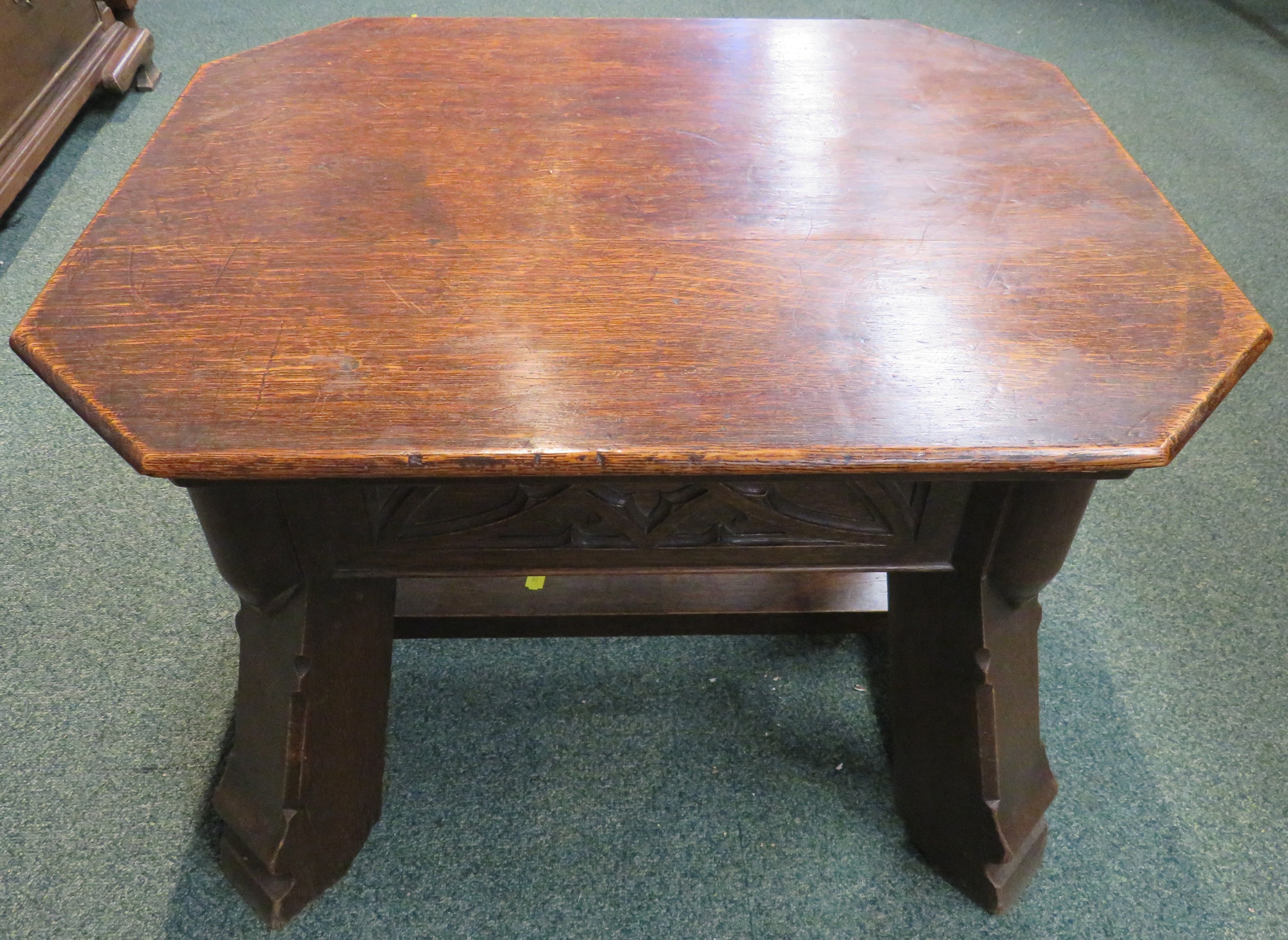 Gothic style oak stool with foliate carving to the frieze and stout stretchered out swept legs,