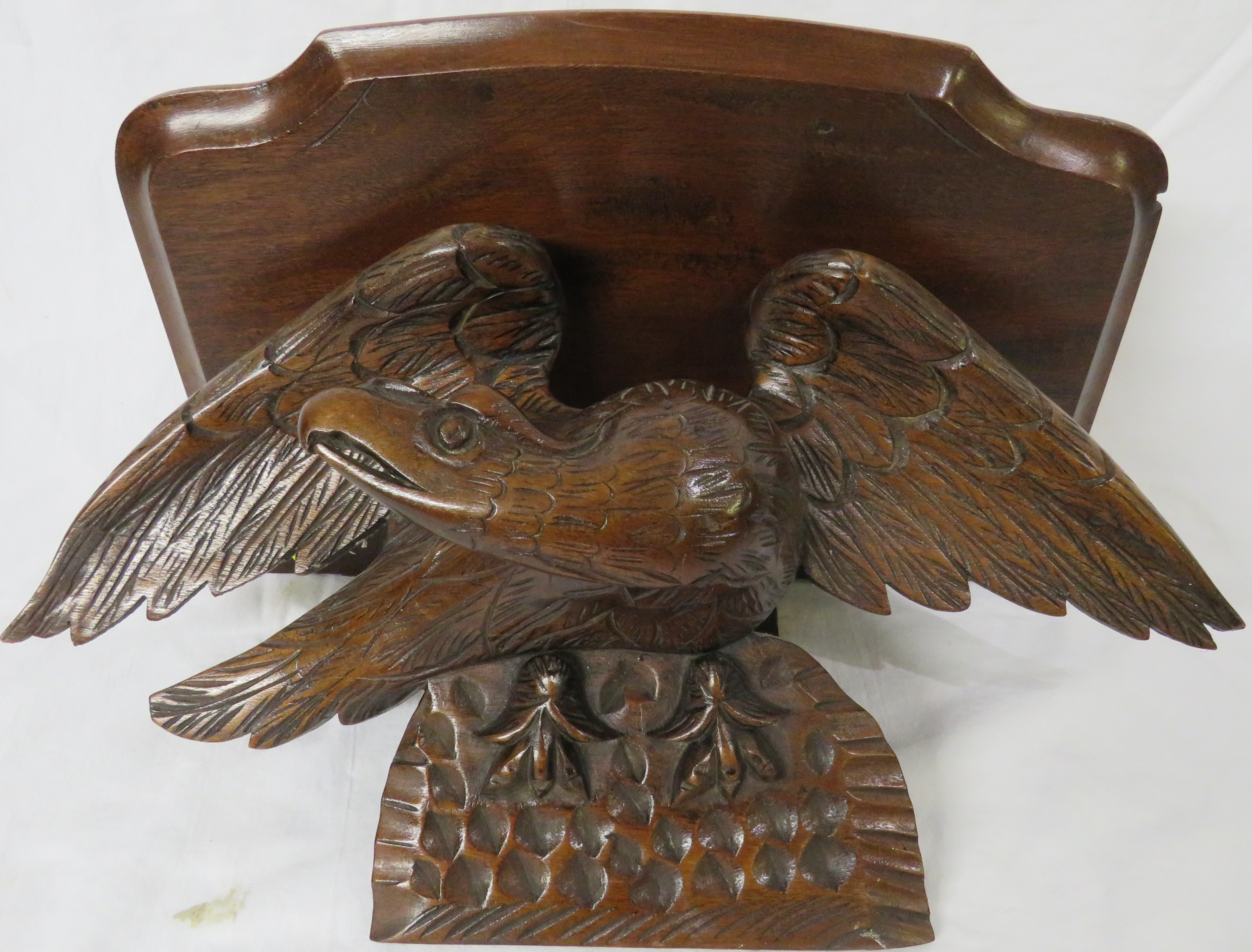 A single-shelf mahogany wall bracket raised and supported on a carved oak eagle, overall height