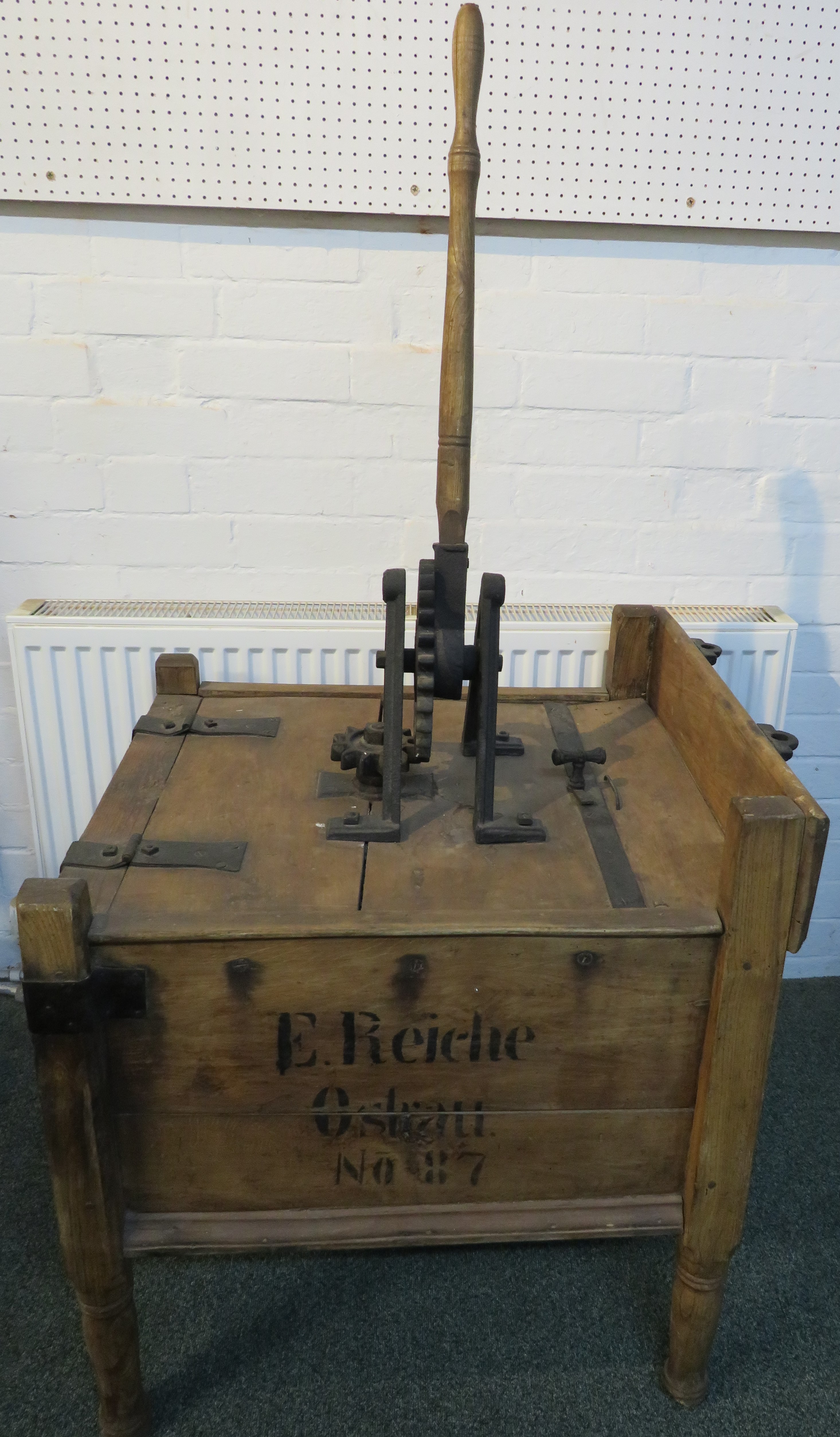 An early wooden tub washing machine fitted with a handle and gear mechanism to the lid driving a