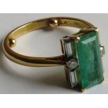 18 carat gold emerald solitaire ring in a setting with six diamonds, the emerald about 11.5mm x 5.