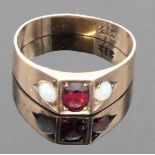 A yellow metal ring set centrally with a garnet 6mm x 4mm, and a small round opal to either side,