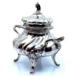 A white metal lidded sucrier bowl of wrythen form with two handles, the lid with a scrolled knop, on