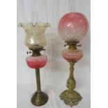 Two brass oil lamps - the first with a reeded column on a stepped circular foot with a ruby glass
