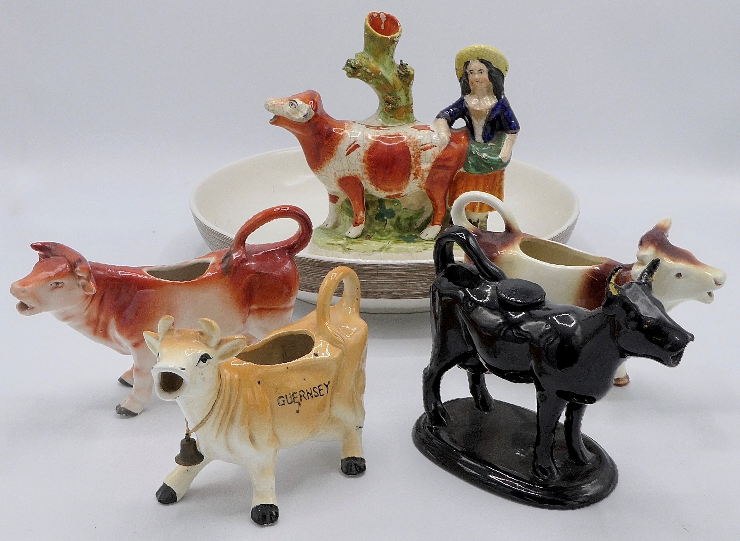 Four cow cream jugs, a Staffordshire pottery group of woman and cow (height 19cm), and a Next