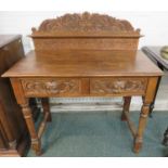 An oak desk or hall table with two drawers carved with foliage and green man mask lug handles, the