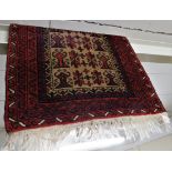 RED GROUND WOOLLEN FLOOR RUG WITH GEOMETRIC PATTERN AND TASSELLED ENDS