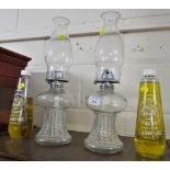 PAIR OF CLEAR GLASS OIL LAMPS AND TWO BOTTLES OF LAMP OIL