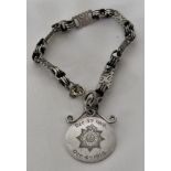 WHITE METAL BRACELET WITH SMALL CIRCULAR PENDANT MARKED FOR DEVONSHIRE REGIMENT ARMY CYCLIST CORP