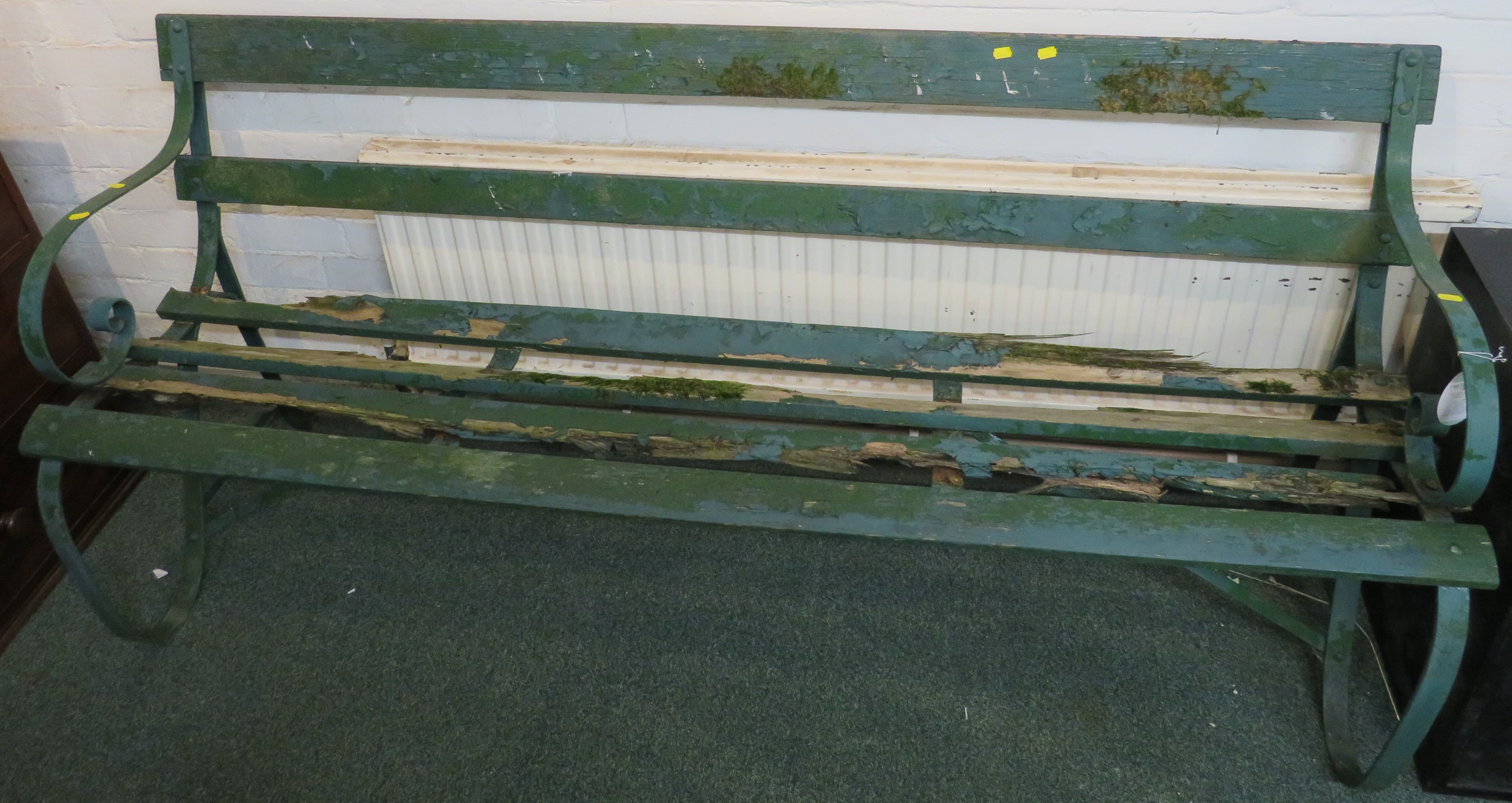 A wooden slatted garden bench with scrolled wrought metal ends, painted green, height 80cm, length