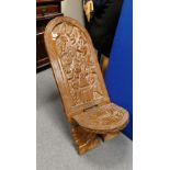 Profusely carved hardwood African two piece chair depicting tribal scenes,