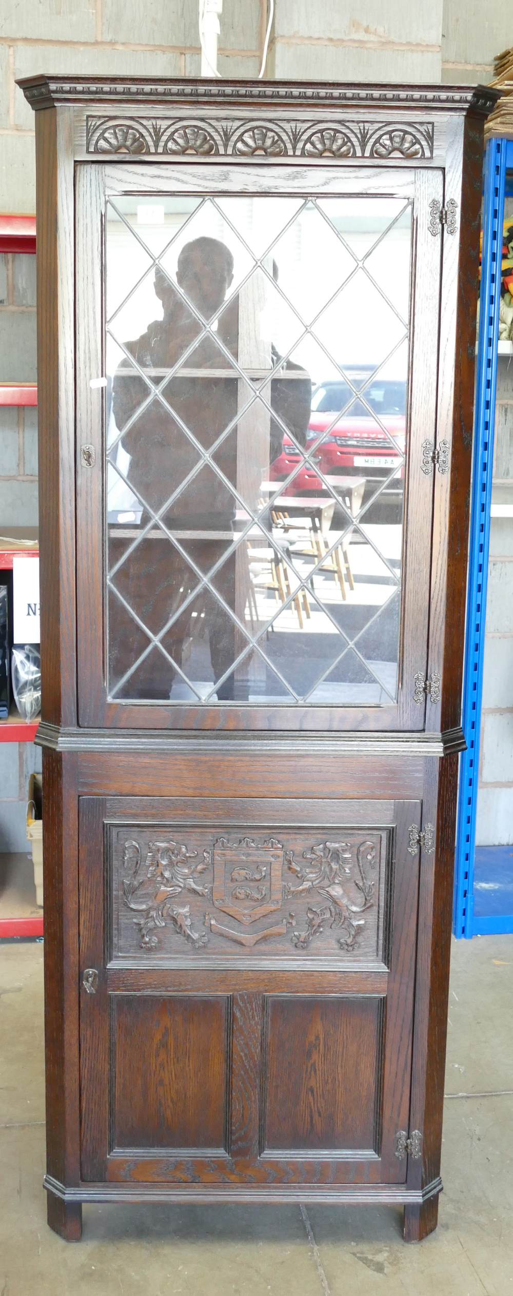 Furniture: Oak priory style glazed corner cupboard with coat of arms motif to lower door.