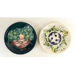 Moorcroft plates: One plate decorated in a landscape design and the other with berries and leaves,