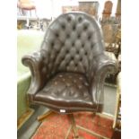 An old brown leather button back armchair on revolving base.