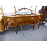 A Georgian mahogany bow front sideboard with central drawers flanked by cupboards on square legs