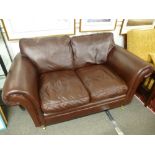 A Laura Ashley brown leather two seat settee on turned front legs