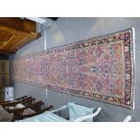 An antique Persian runner with repeated floral design, blue bordered