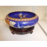 A Cloisonné enamelled shallow bowl decorated flowers and birds on a carved wooden stand