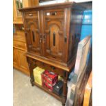 A continental style oak two door cupboard having arched doors on a similar 2 drawer base with turned