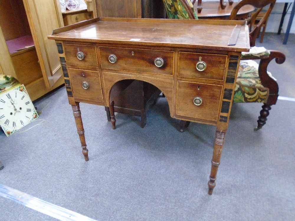 An antique mahogany writing table with five drawers with rosewood inlaid panels on turned legs,