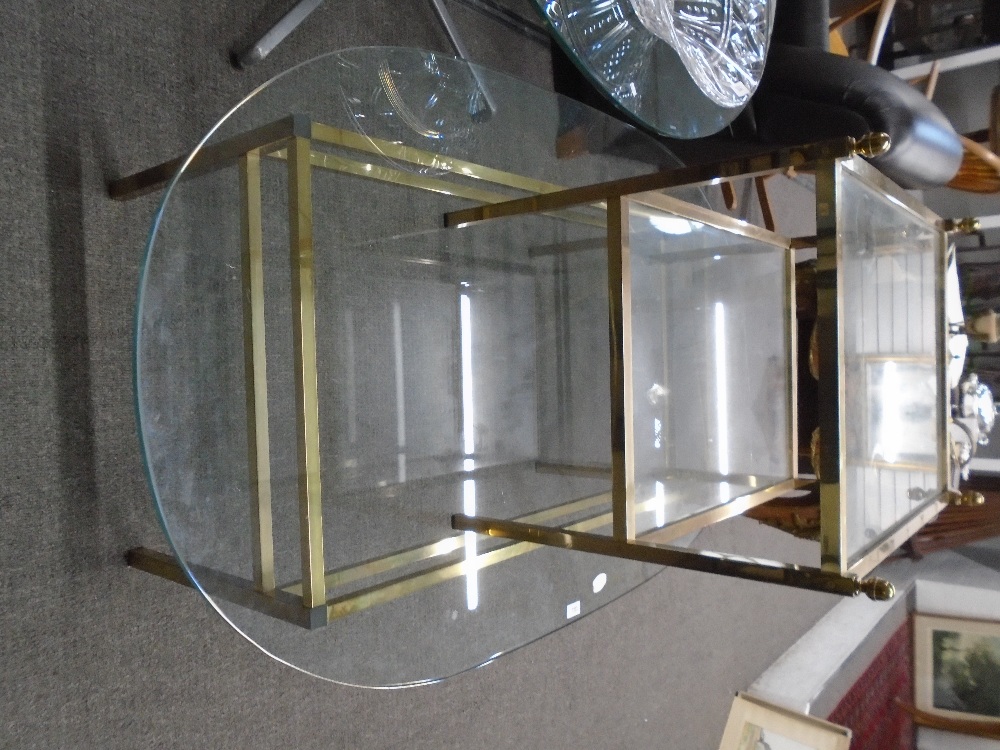 An oval glass top coffee table with a brass effect base to include a similar two tier table