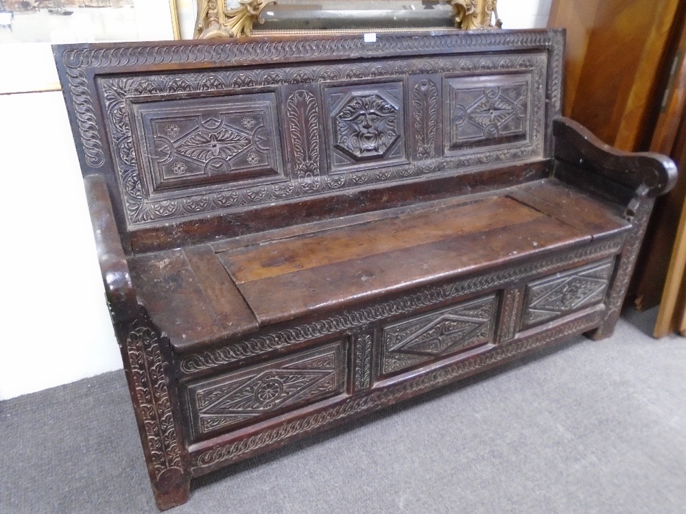 An 18th century and later carved oak monksbench with box seat and scroll arms, probably continental,