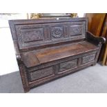 An 18th century and later carved oak monksbench with box seat and scroll arms, probably continental,