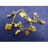 9ct yellow gold charm bracelet hung with various charms including V.W Beetle car, champagne bottle