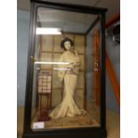 Black and glass case containing a figure of a Geisha girl