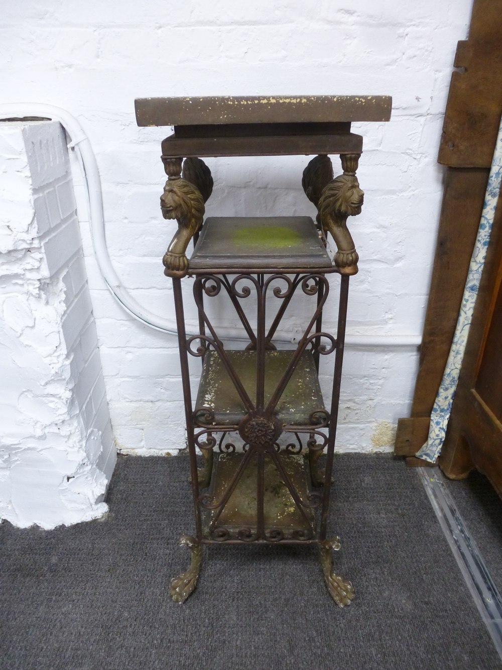 A metal four tier stand decorated lion's heads on paw feet, height 91 cms