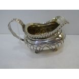 George III silver milk jug, half gadroon decoration, leaf pattern handle on 4 leaf and shell pattern