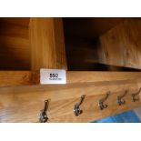 A contemporary wooden floating shelf unit with coat hooks below